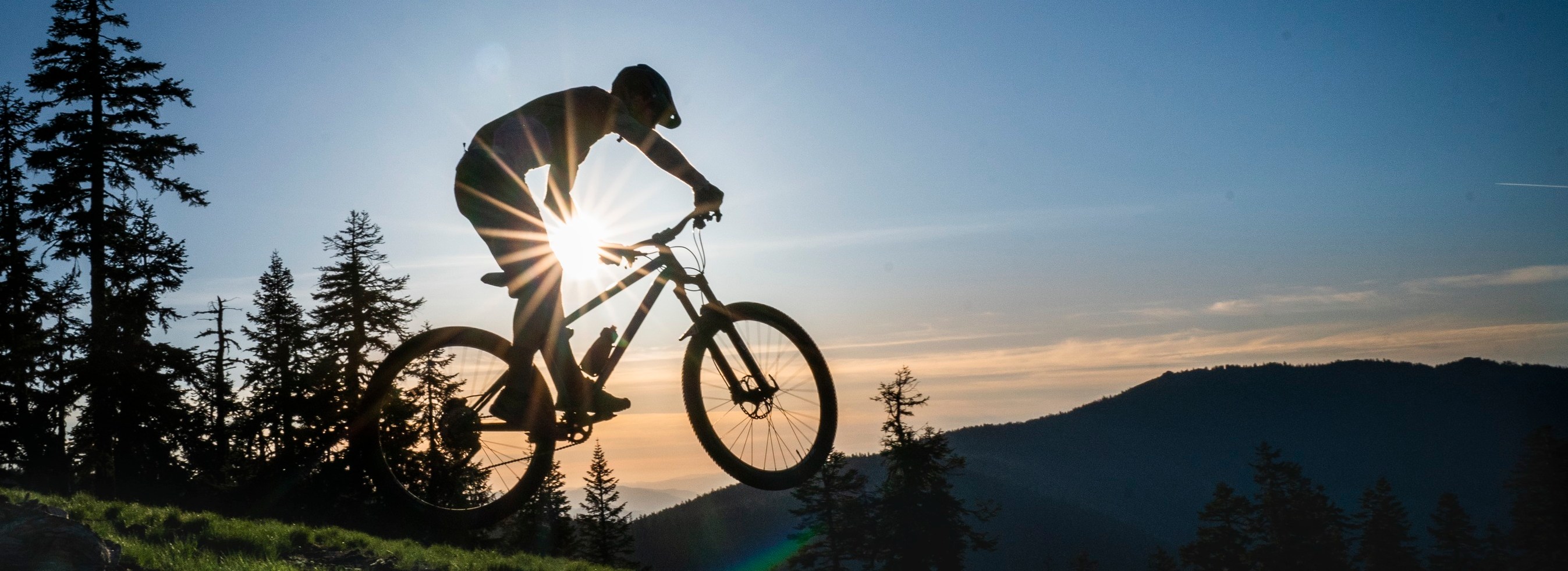Person mountain biking on a ridge line at sunset