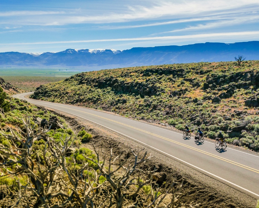 image of cyclists riding the oregon outback scenic bikeway with mountains in the background