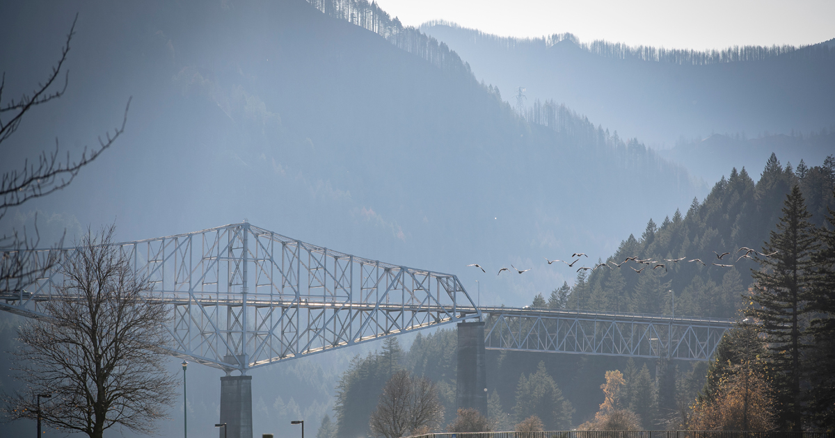Bridge spanning river with mountains in the background