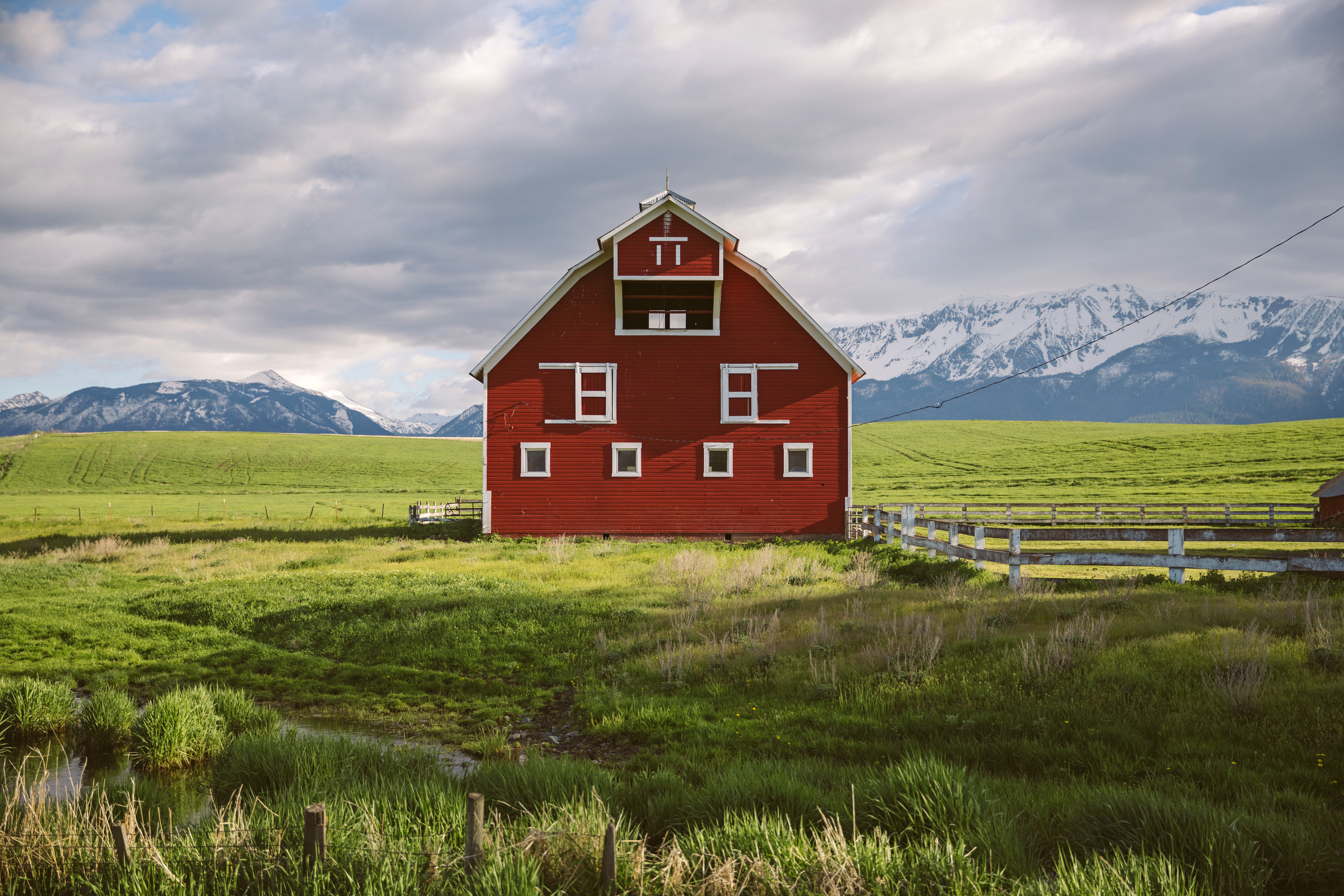 Red barn sitting center in beautiful green landscape in the Wallowas inEastern Oregon.
