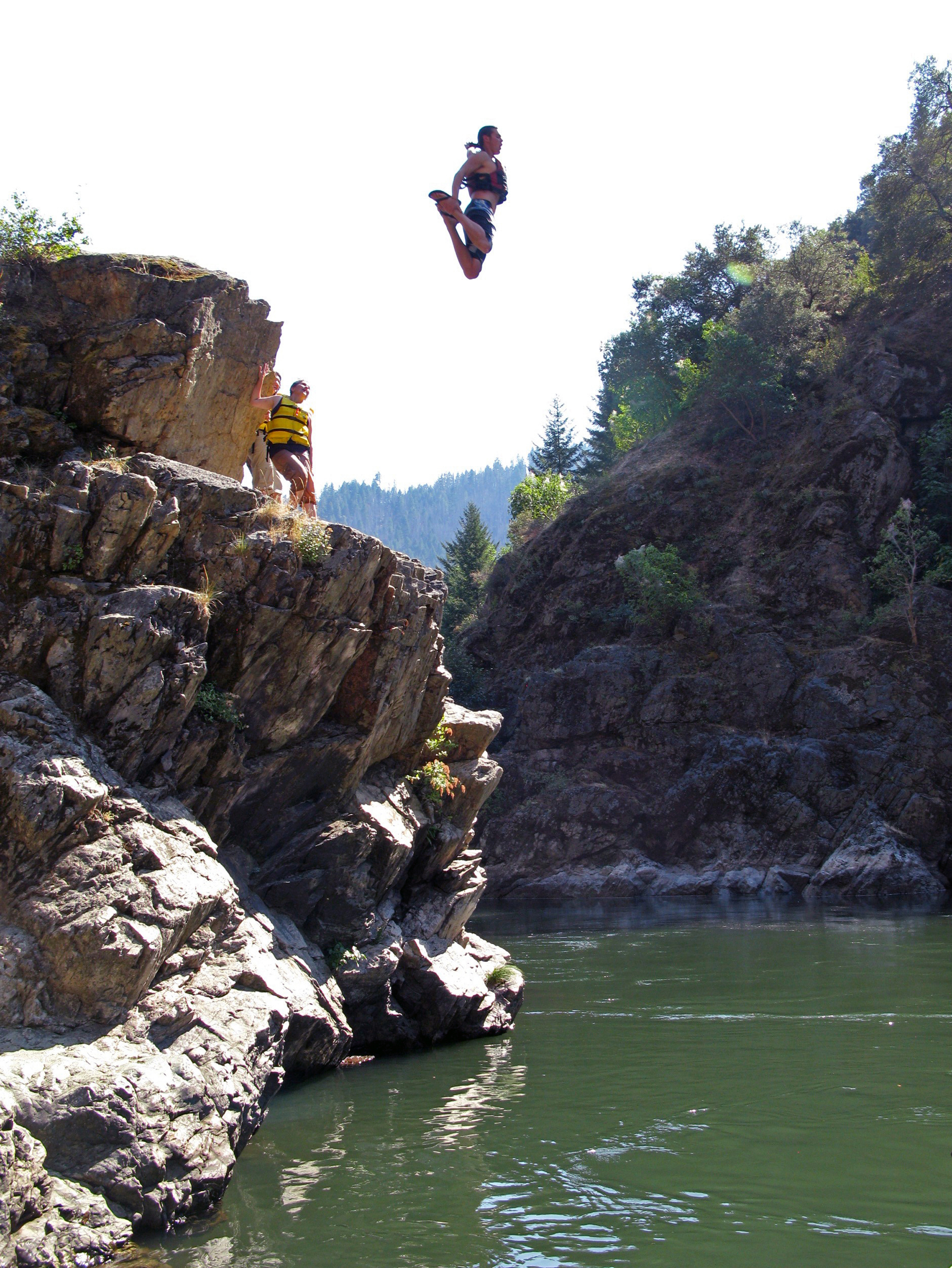 Woman jumping off rock into a river