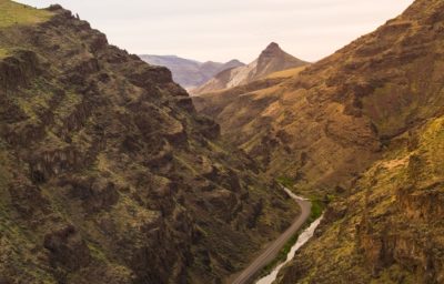 Sunlit rocky hillsides and creek in Eastern Oregon