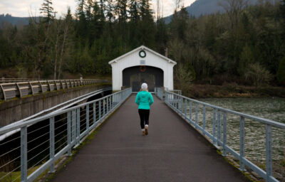 Woman running across white covered bridge.