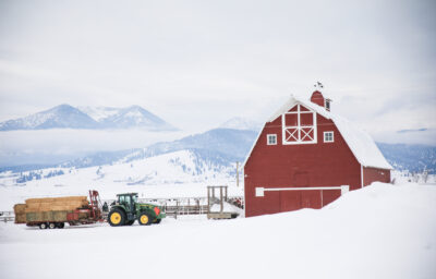 Red barn, tractor pulling hay in snowy Eastern Oregon.