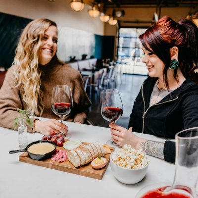 Two women enjoying wine and appetizers at Stem Wine Bar in Portland.