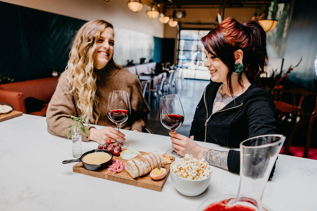 Two women enjoying wine and appetizers at Stem Wine Bar in Portland.