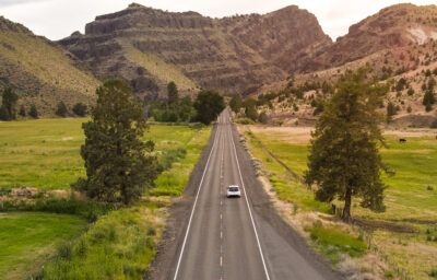 Electric vehicle driving down byway in Eastern Oregon.