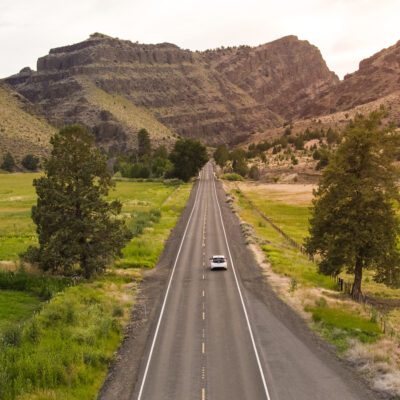 Electric vehicle driving down byway in Eastern Oregon.