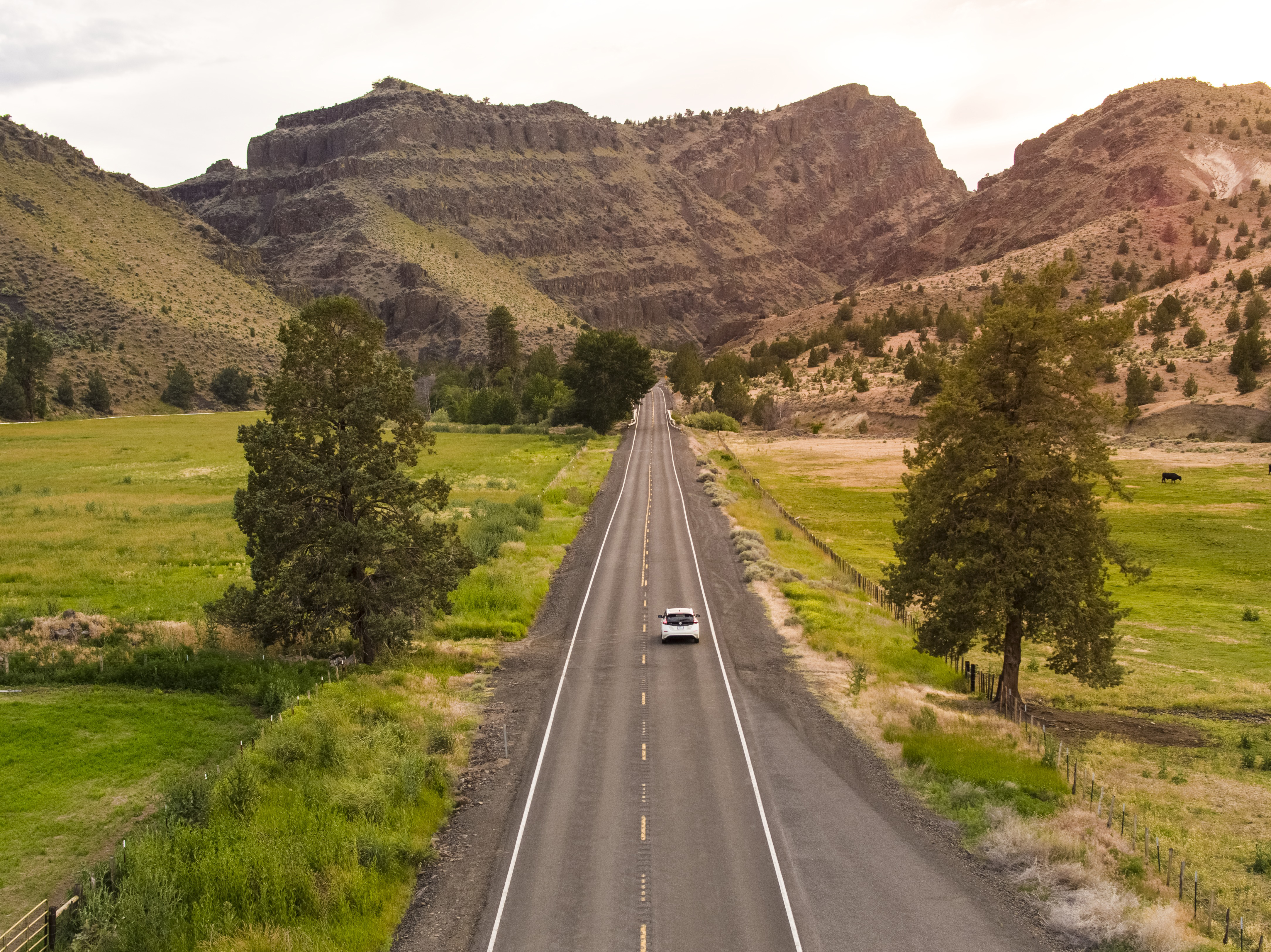 Electric vehicle driving down byway in Eastern Oregon.