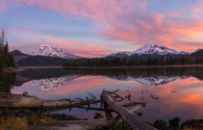 Coastal image at sunset with snowy mountain tops in the distance.