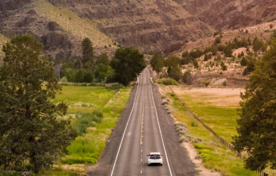 Electric vehicle driving down long stretch of highway in Eastern Oregon