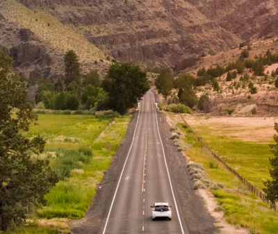 Electric vehicle driving down long stretch of highway in Eastern Oregon