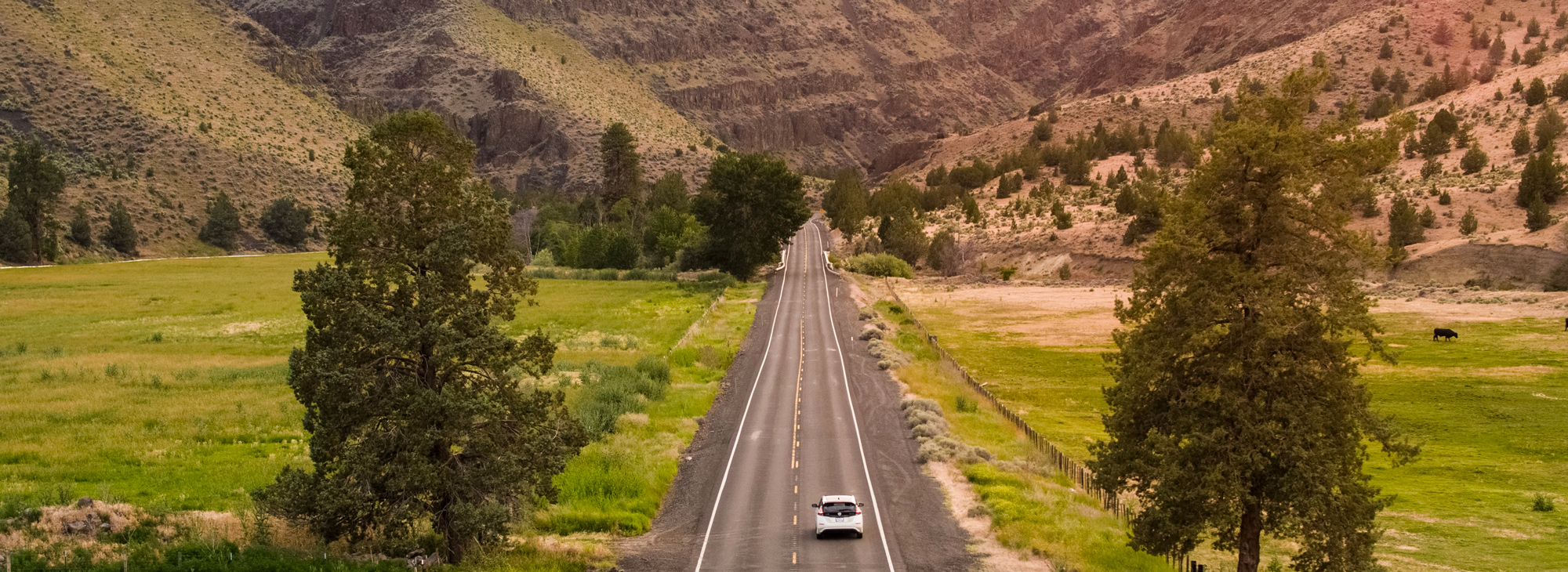 Electric vehicle driving down long stretch of highway in Eastern Oregon