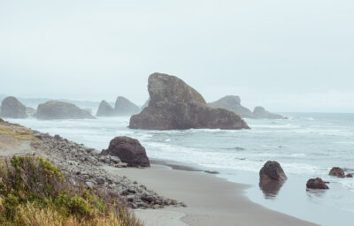 Rocky Oregon Coast shore with ocean and large rocks in the distance.