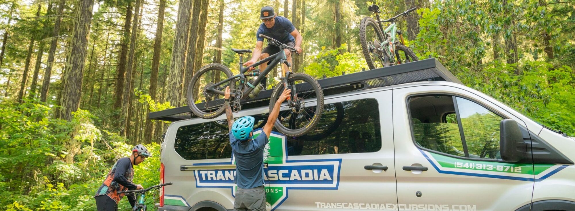 Person unloading mountain bikes from a tour van in the forst.