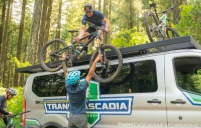 Person unloading mountain bikes from a tour van in the forst.