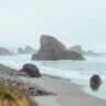 Rocky Oregon Coast shore with ocean and large rocks in the distance.