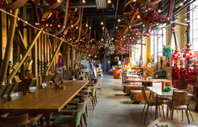 Beautiful dining room with industry lights, long tables and colorful seating.