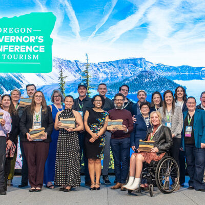 A group of people standing on stage accepting Travel & Tourism Achievement awards.