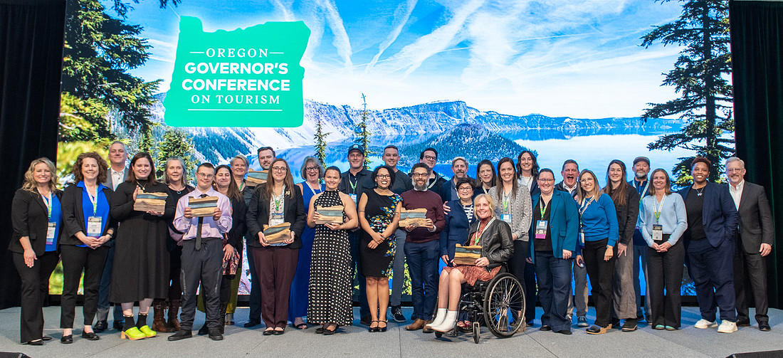 A group of people standing on stage accepting Travel & Tourism Achievement awards.
