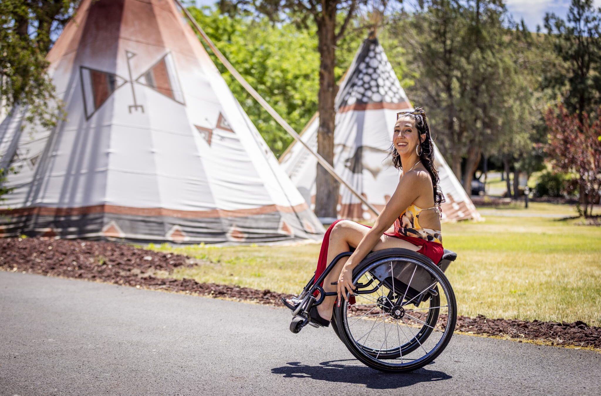 Woman in wheel chair pops a wheelie in front of teepees at Kah-Nee-Ta Resort